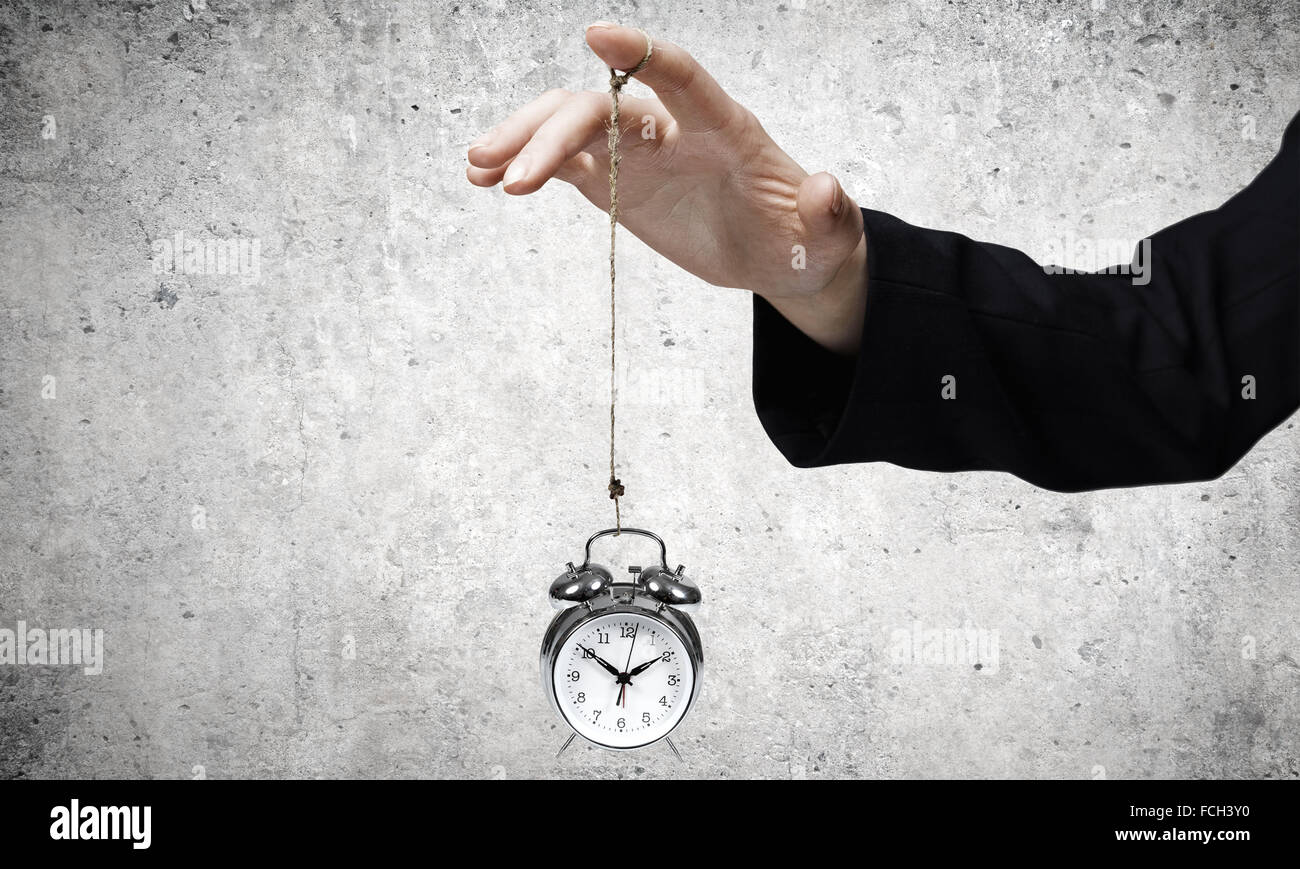 Close up of businessman holding clock on rope Stock Photo - Alamy