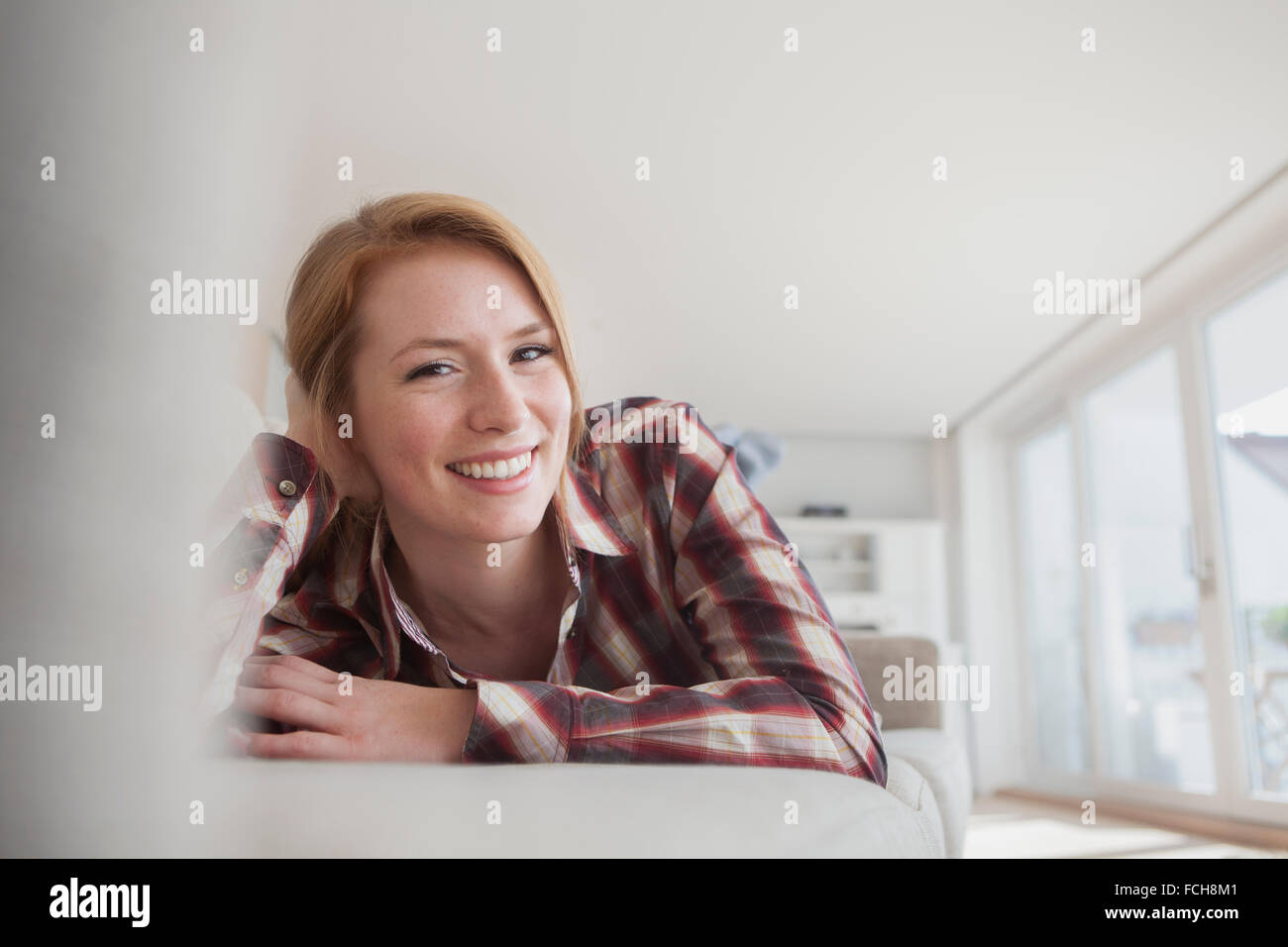 Portrait of smiling young woman relaxing on the couch at home Stock ...