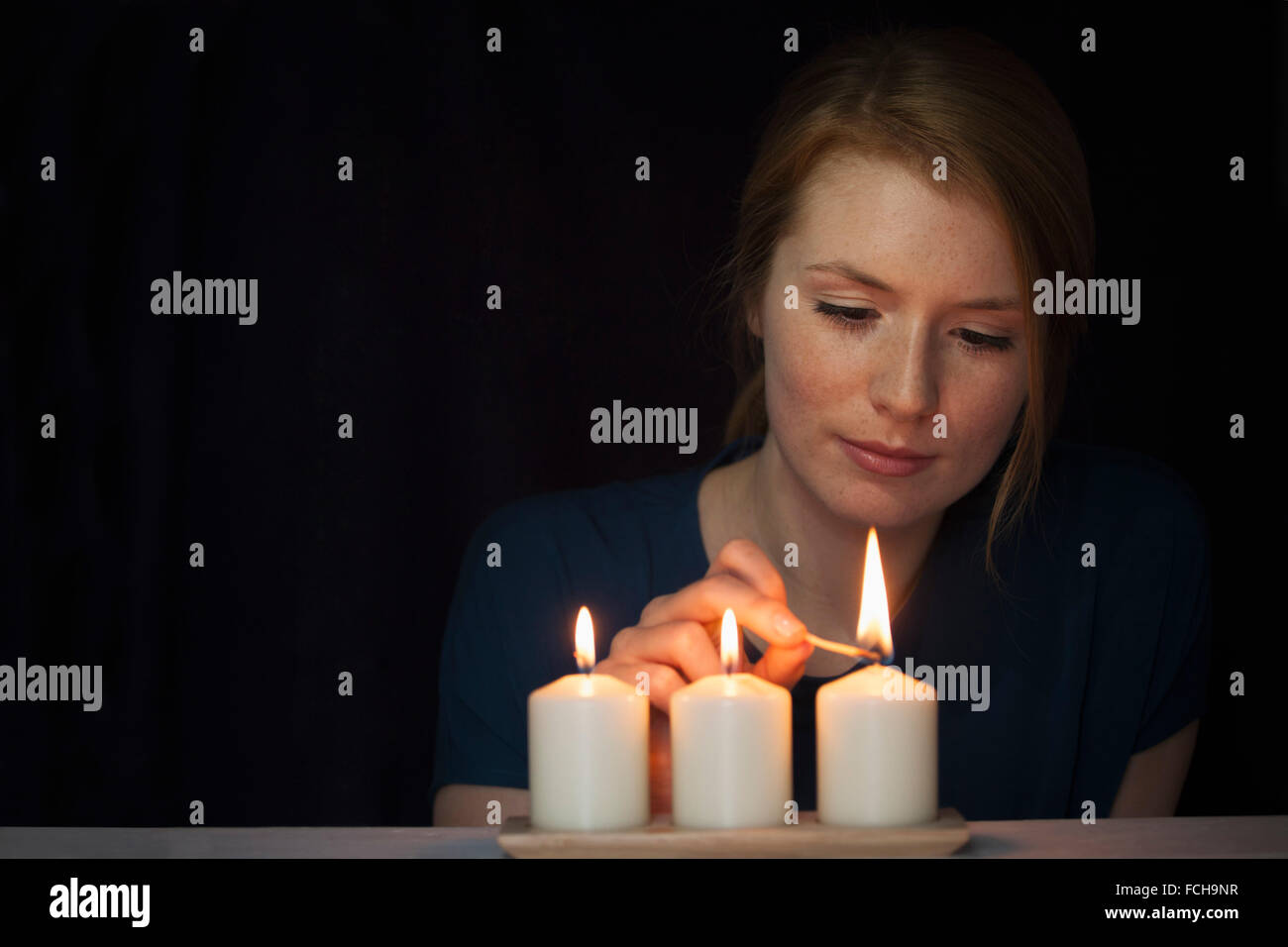 Portrait of young woman lighting candles Stock Photo