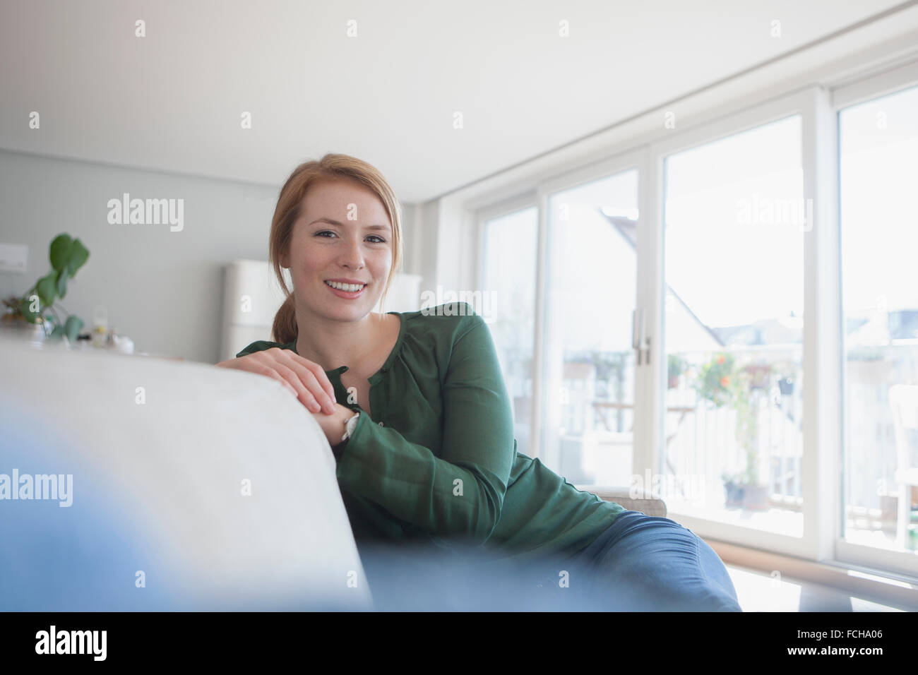 Portrait of smiling young woman sitting on the couch at home Stock ...