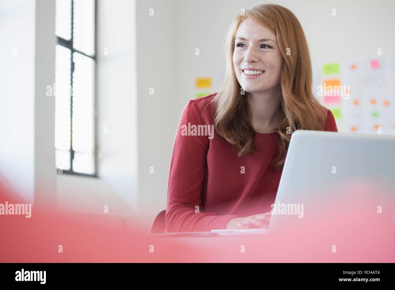 Young woman in office using laptop Stock Photo