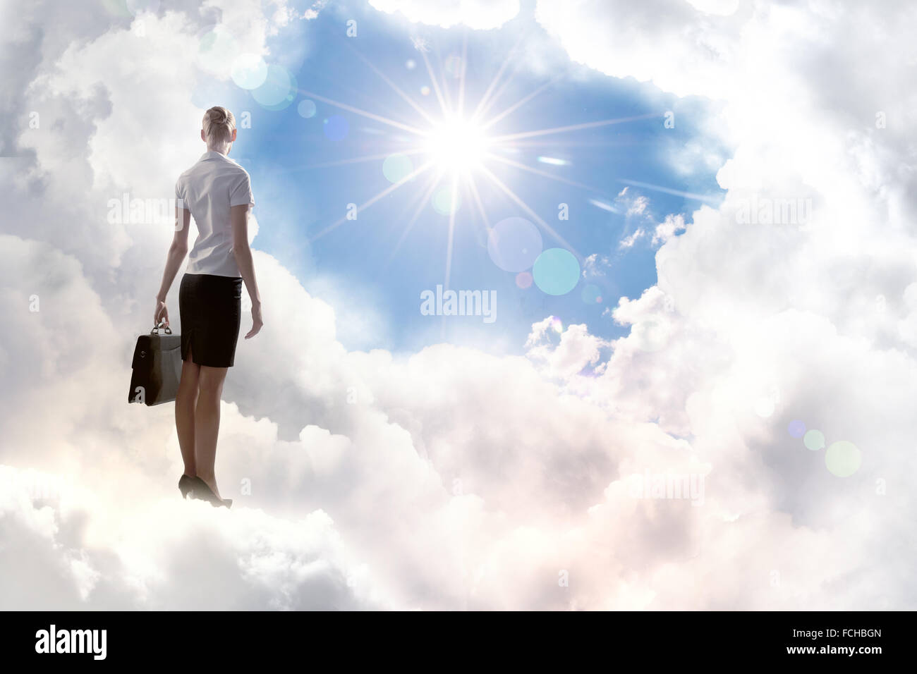 Rear view of businesswoman with suitcase standing on cloud Stock Photo ...