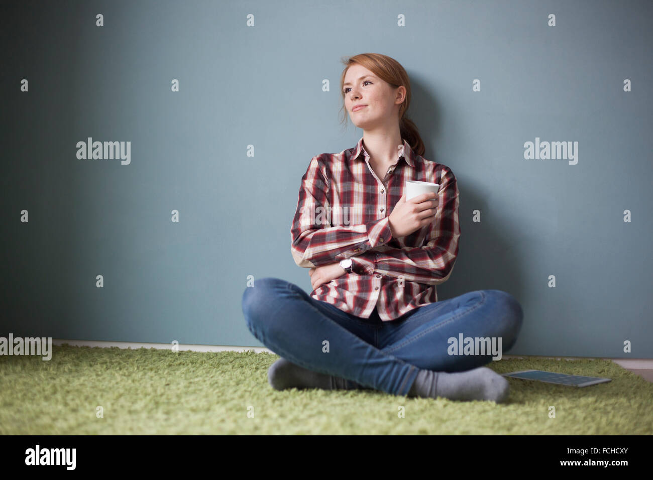 Smiling young woman sitting on the floor cup of coffee Stock Photo - Alamy