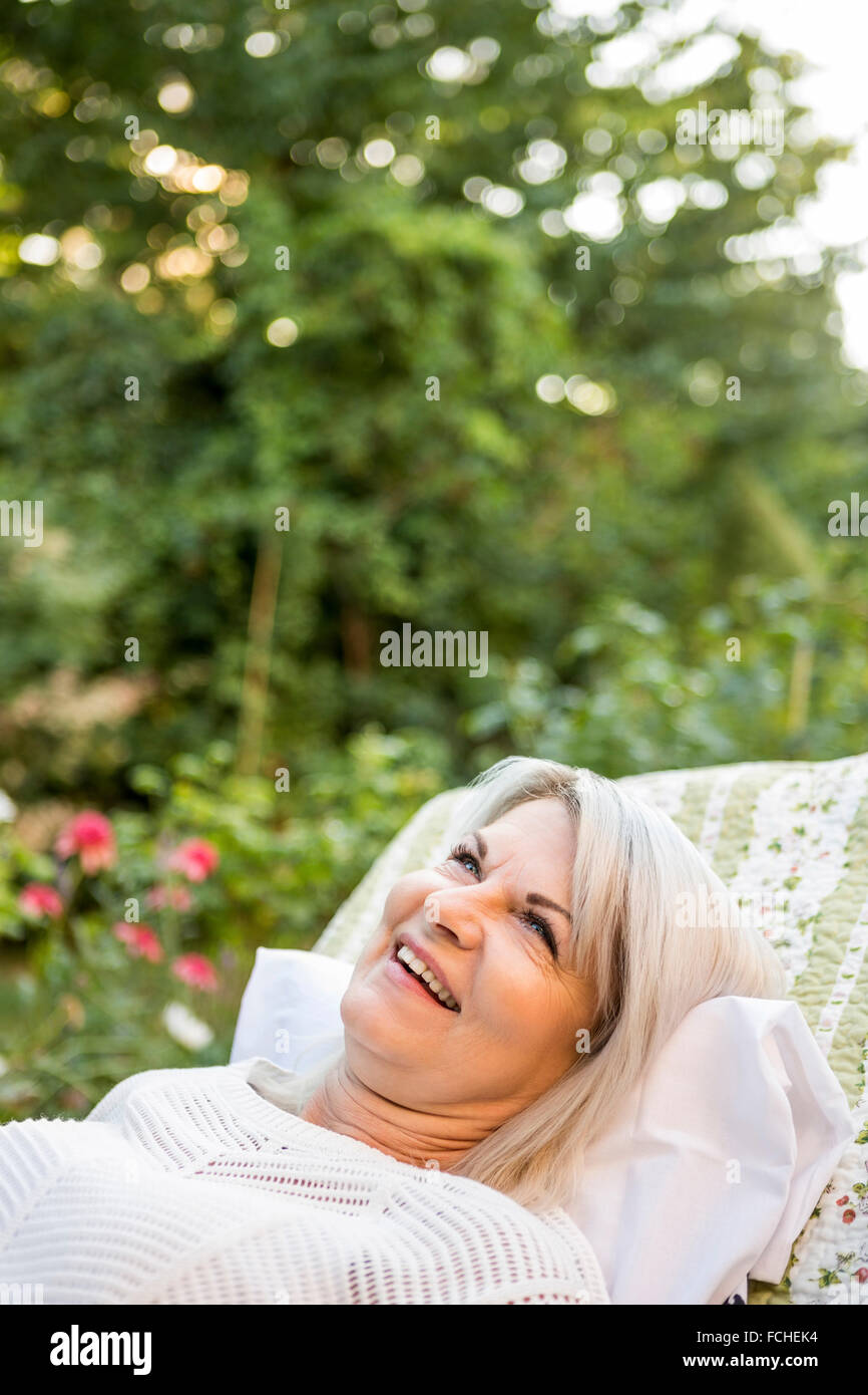 Smiling mature woman relaxing in garden Stock Photo - Alamy