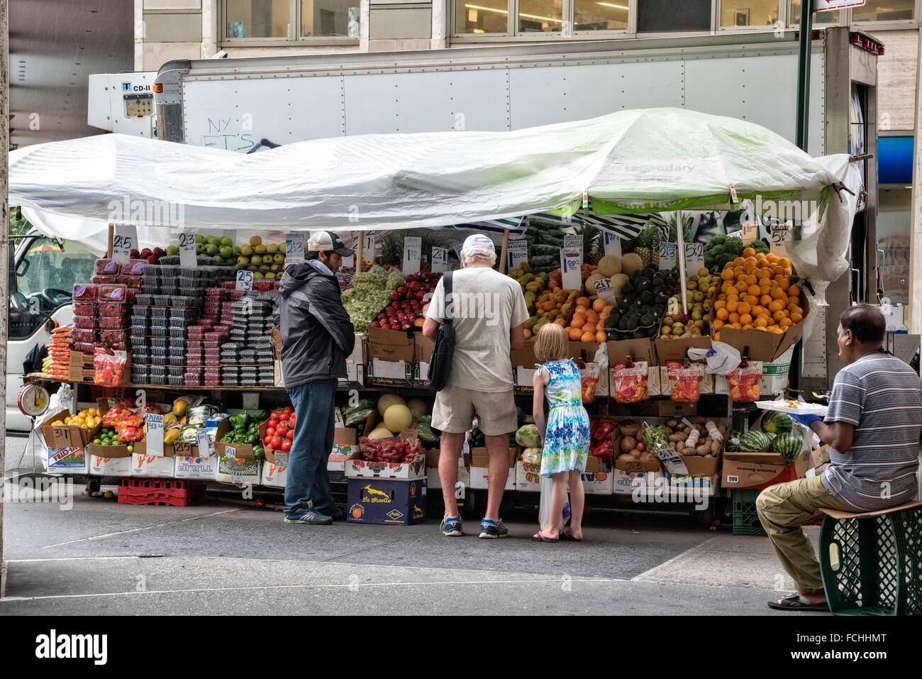 Elderly Man and Little Girl buying produce from a street vending cart