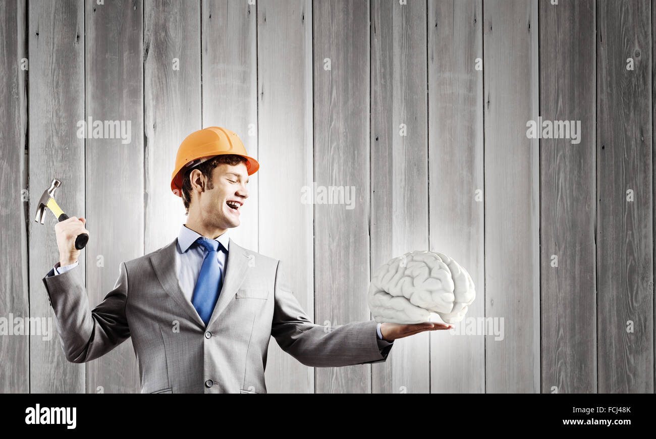 Young businessman with hammer and human brain in hand Stock Photo Alamy