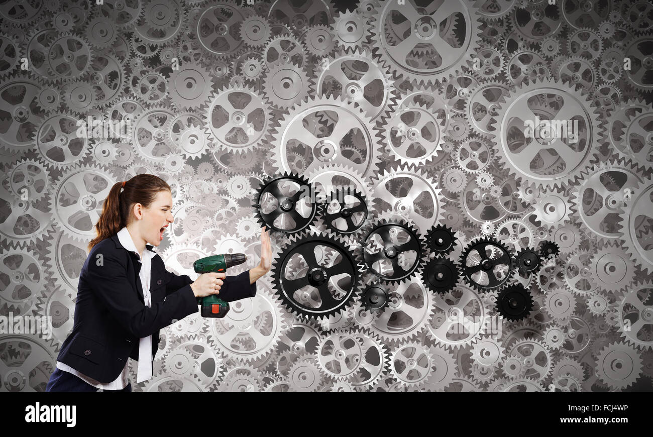 Young businesswoman using drill to fix gears mechanism Stock Photo Alamy