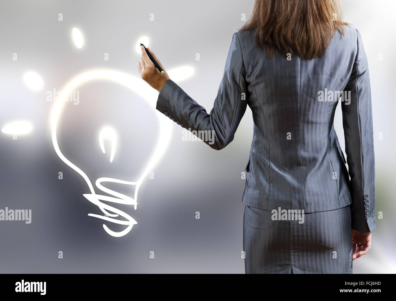 Rear view of businesswoman drawing bulb with pen Stock Photo - Alamy