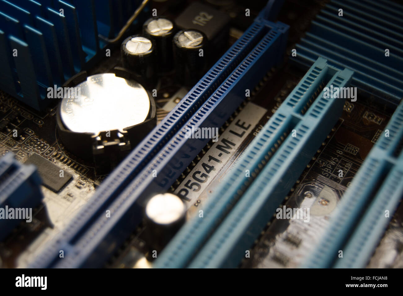 A PC motherboard's PCI-E slots and battery. Stock Photo