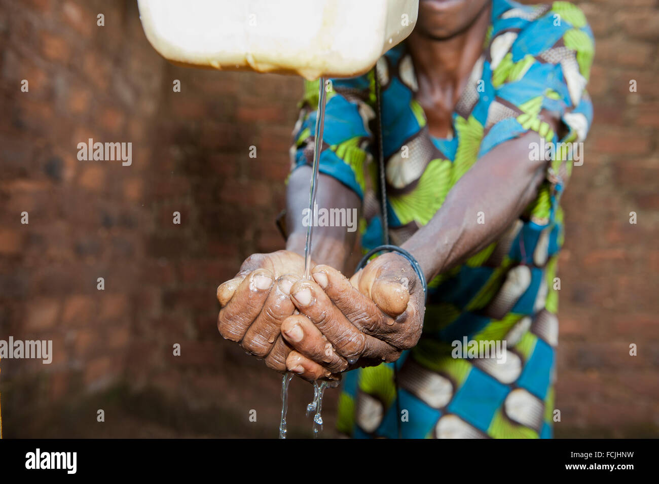 Lady washing hands from a 'Tip Tap' an efficent way to clean hands without wasting water. Uganda. Stock Photo