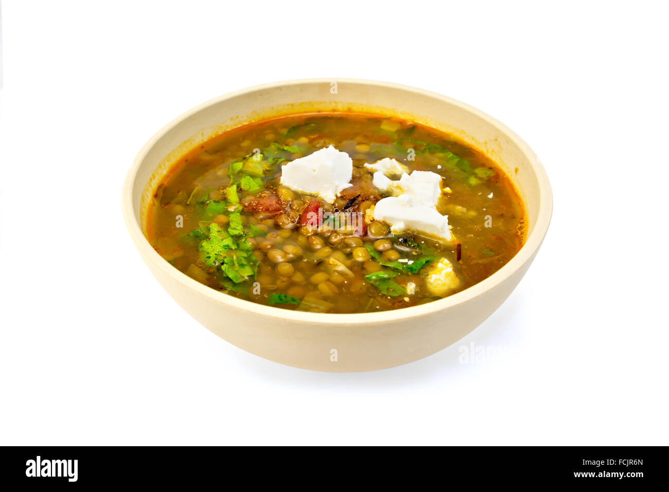 Lentil soup with spinach, tomatoes and feta cheese in a yellow dish isolated on white background Stock Photo