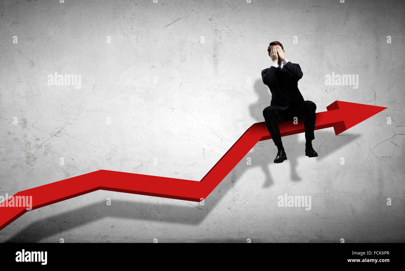 Young businessman sitting on red arrow with closed eyes Stock Photo - Alamy