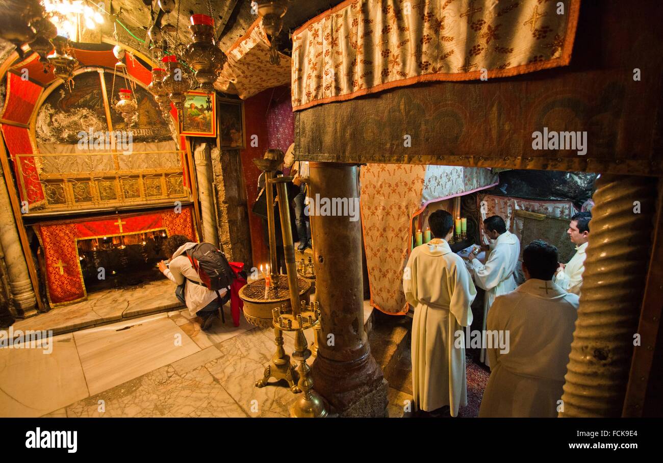 Priest and tourists praying in the Church of the Nativity, Grotto of