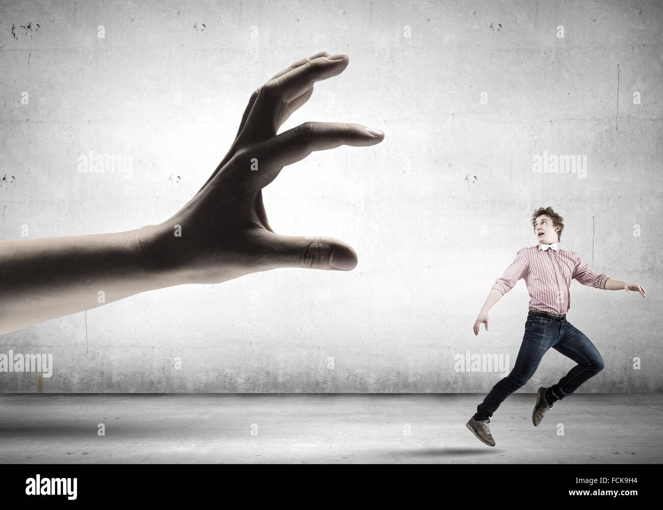 Young man in casual running away from big hand Stock Photo - Alamy