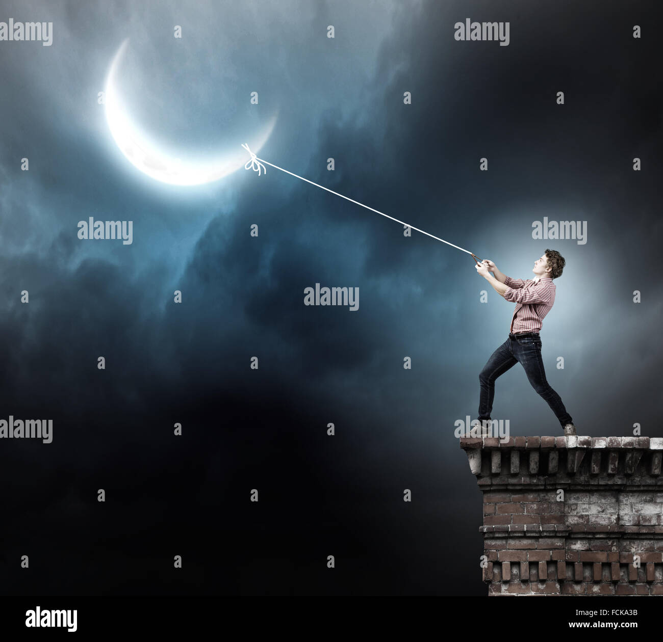 Young man in casual catching moon with rope Stock Photo - Alamy