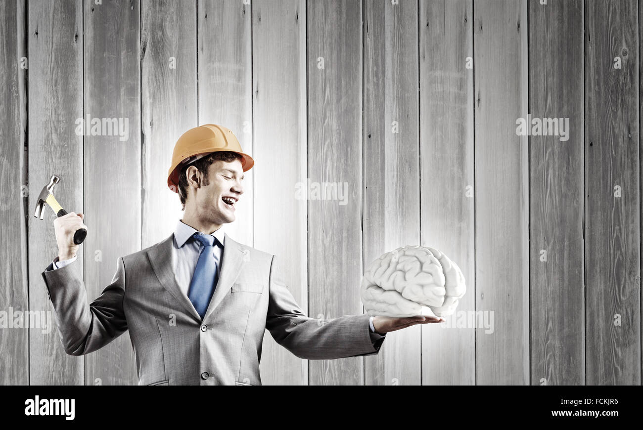 Young businessman with hammer and human brain in hand Stock Photo Alamy