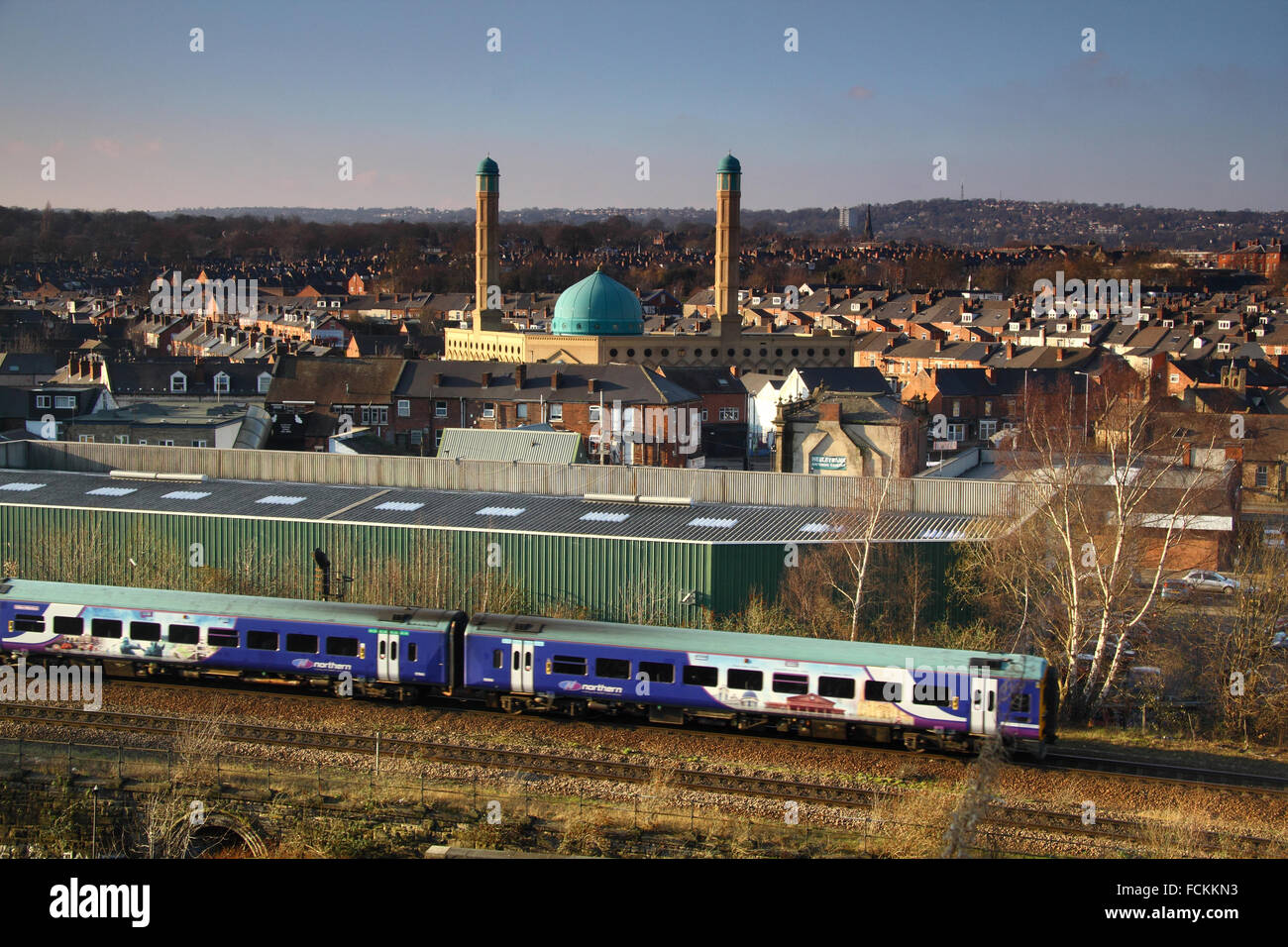 A train approaches Sheffield city centre with views over the Madina Masjid mosque, housing and distant hills, Yorkshire England Stock Photo