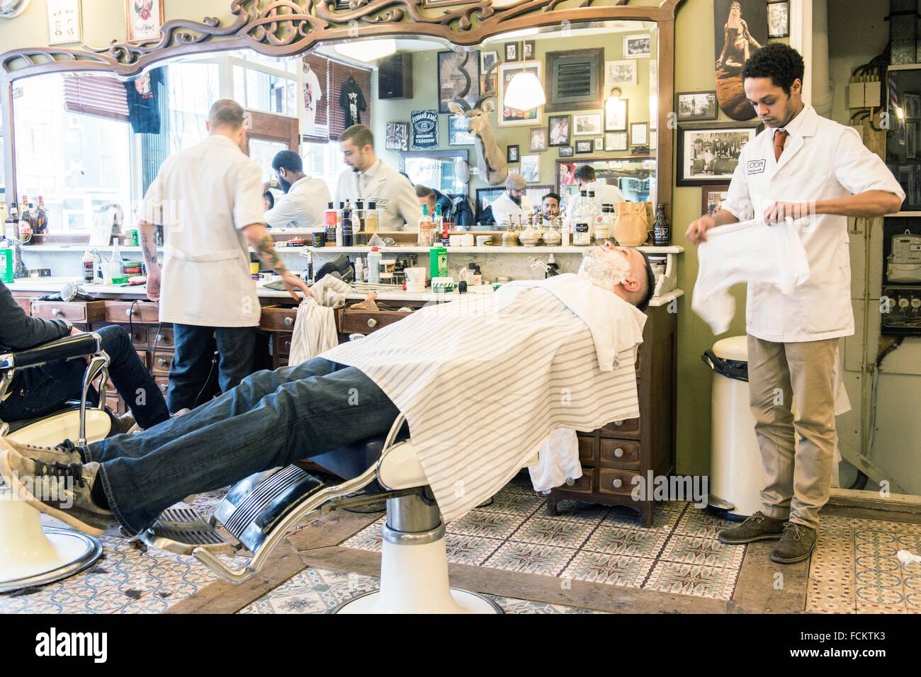 Rotterdam, Netherlands. Barber store Schorem. Male customer lying back