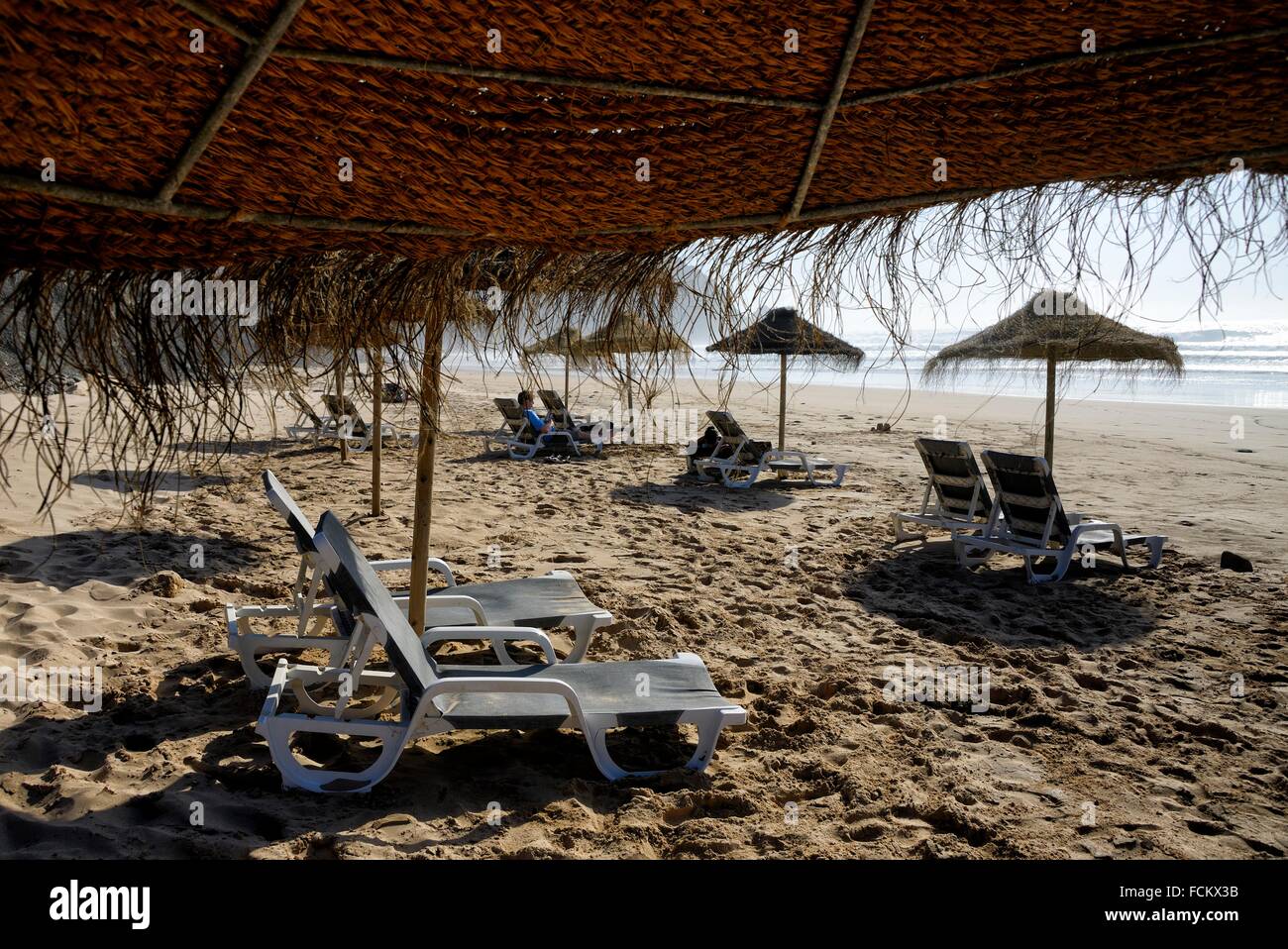 beach umbrellas and sunloungers at almost empty beach, Praia do Castelejo, Castelejo beach, near Vila Do Bispo, close to Stock Photo