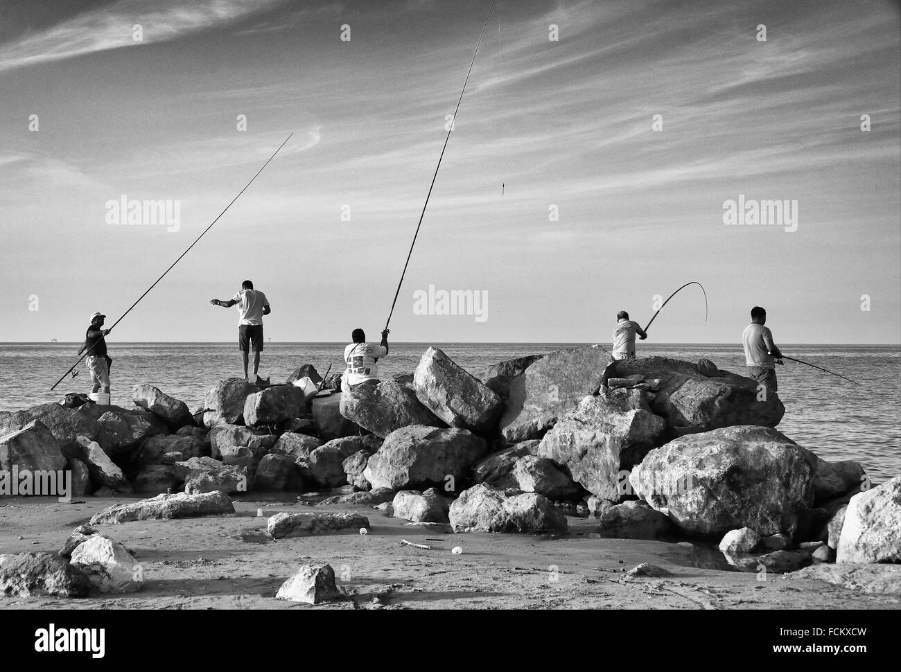 group of men fishing in traditional way - with fishing rods directly from  Mediterranean Sea, beach in Montesilvano, province of Stock Photo - Alamy