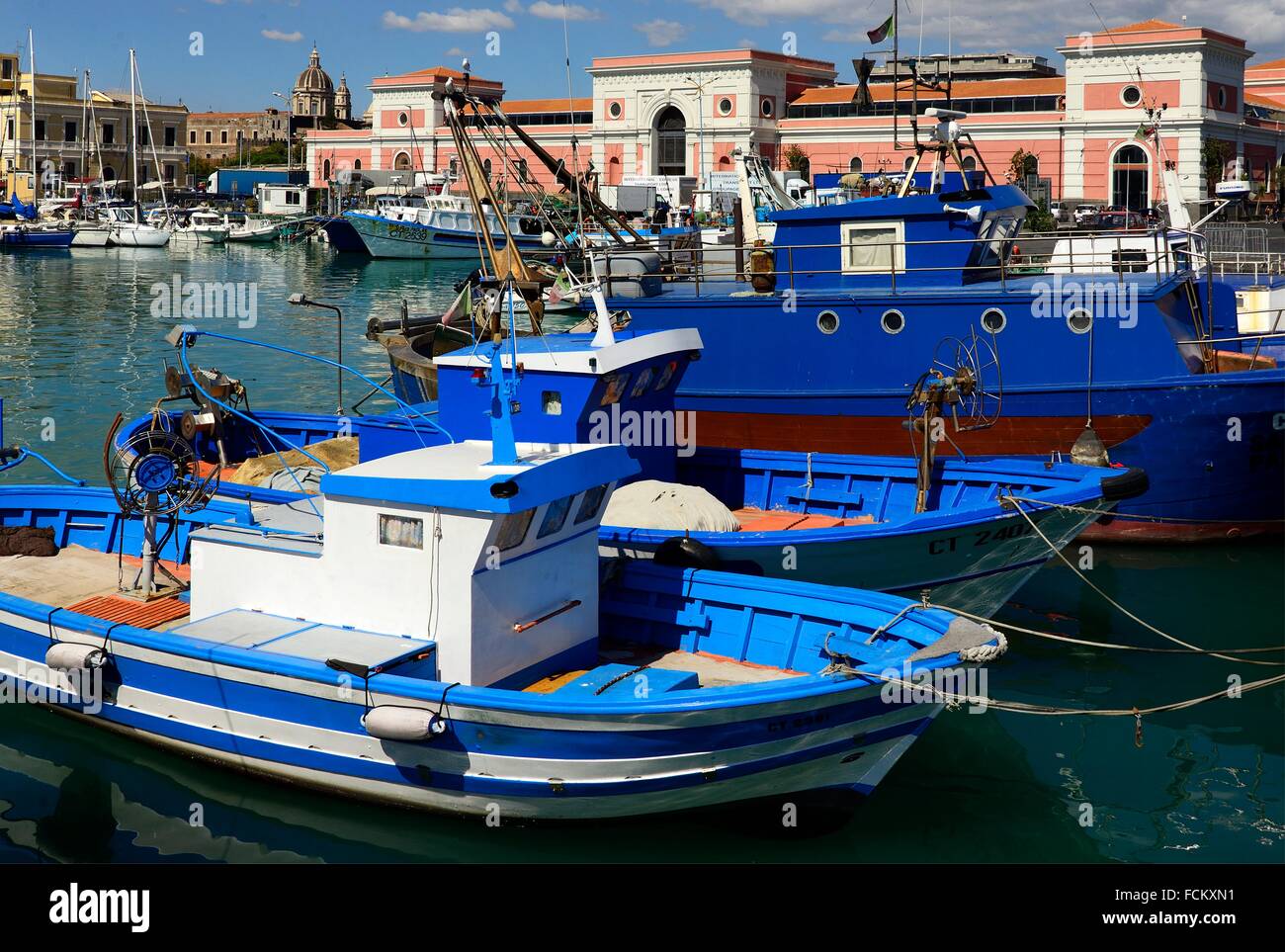 Catania harbour, fishing boats, old town and dome of famous Cathedral in far background, Sicily, Italy. Stock Photo