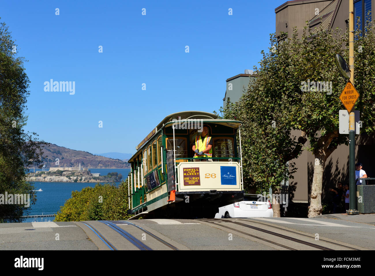 Cable car on Hyde Street at junction with Lombard Street, with distant view of Alcatraz Island, San Francisco, California, USA Stock Photo