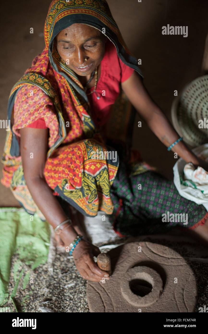 Woman of Bhil tribe grinding grain in India Stock Photo