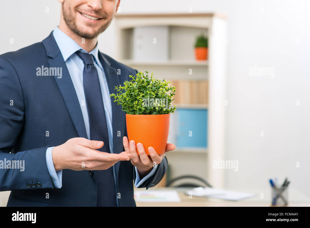 Vivacious office worker holding flower pot Stock Photo - Alamy
