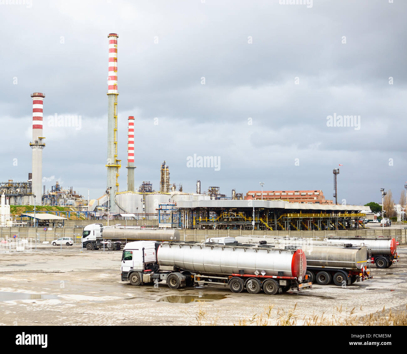 Oil refinery industry, smoke stacks and silver tanker lorry or truck in parking Stock Photo