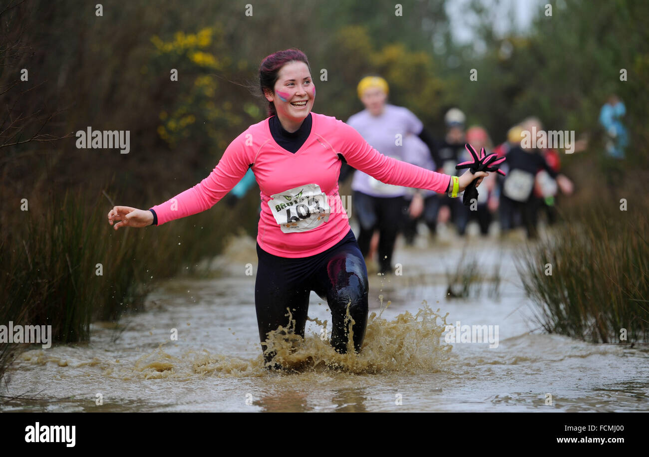 Aldershot, Hants, UK. 23rd January, 2016.  Lizzie Umbers smiles as she  makes her way through the flooded streams of the Brutal women only  10km  race at Long valley Aldershot Hampshire having to break the ice as the make there way around the course .  The recent weather made the Brutal 10km off road course live up to its name as the puddles and streams where up to waste height in many places with early runners having to break the ice as they entered the water.  Credit:  PBWPIX/Alamy Live News Stock Photo