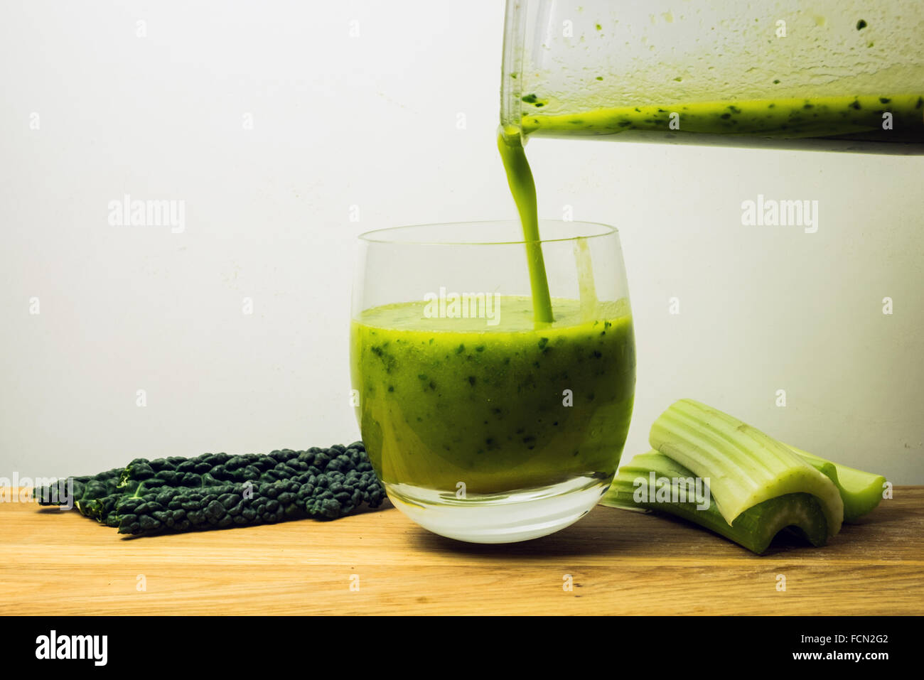 Pouring a glass of green sirtfood kale smoothie Stock Photo