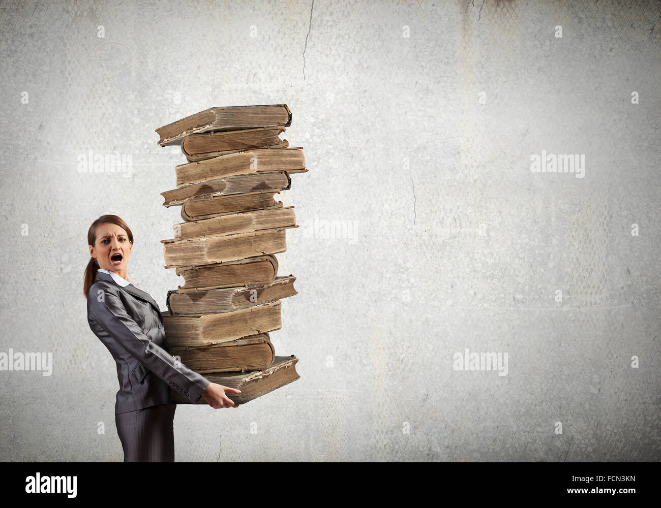 Young businesswoman carrying pile of old books Stock Photo - Alamy