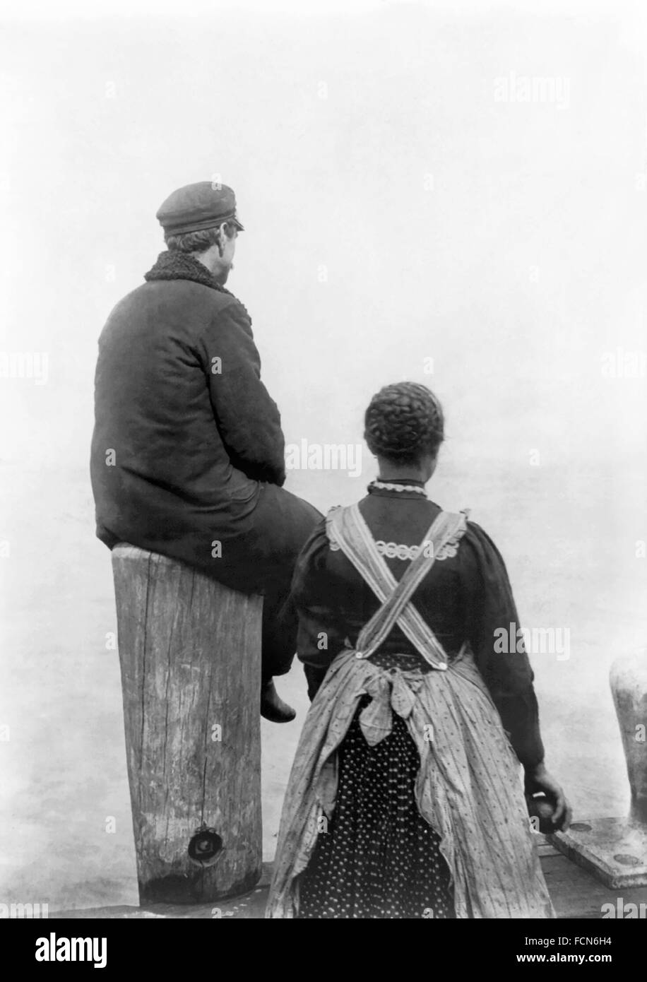 Ellis Island Immigrantst. Two immigrants (?) on the dock at Ellis Island, New York, NY, c.1912. The original photograph is entitled 'Two emigrants on the seashore' (Library of Congress). Stock Photo