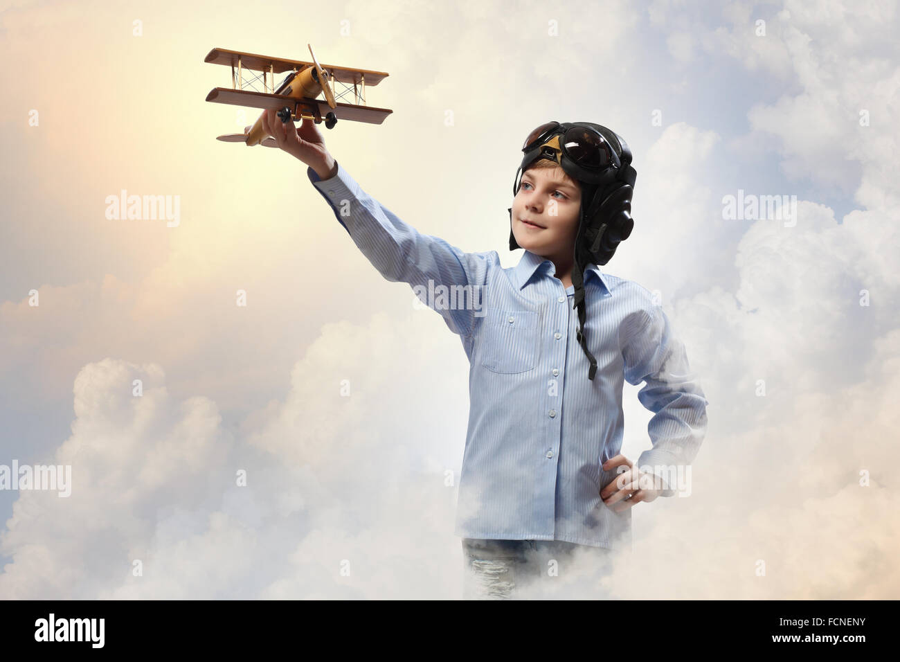 Image of little boy in pilots helmet playing with toy airplane against ...