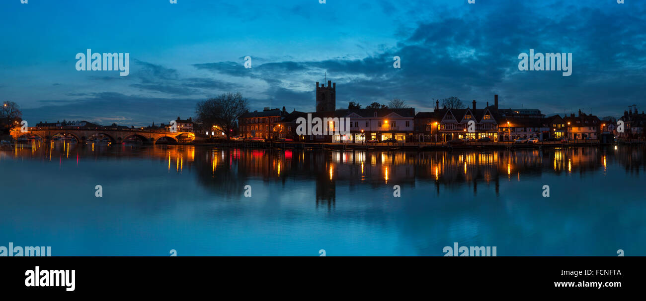 Dusk over the River Thames with the Oxfordshire town of Henley on Thames in the Background. Evening sky is blue and the town is reflected in the river Stock Photo