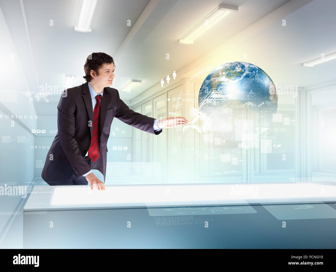 Image of young businessman clicking icon on high-tech picture of globe Stock Photo