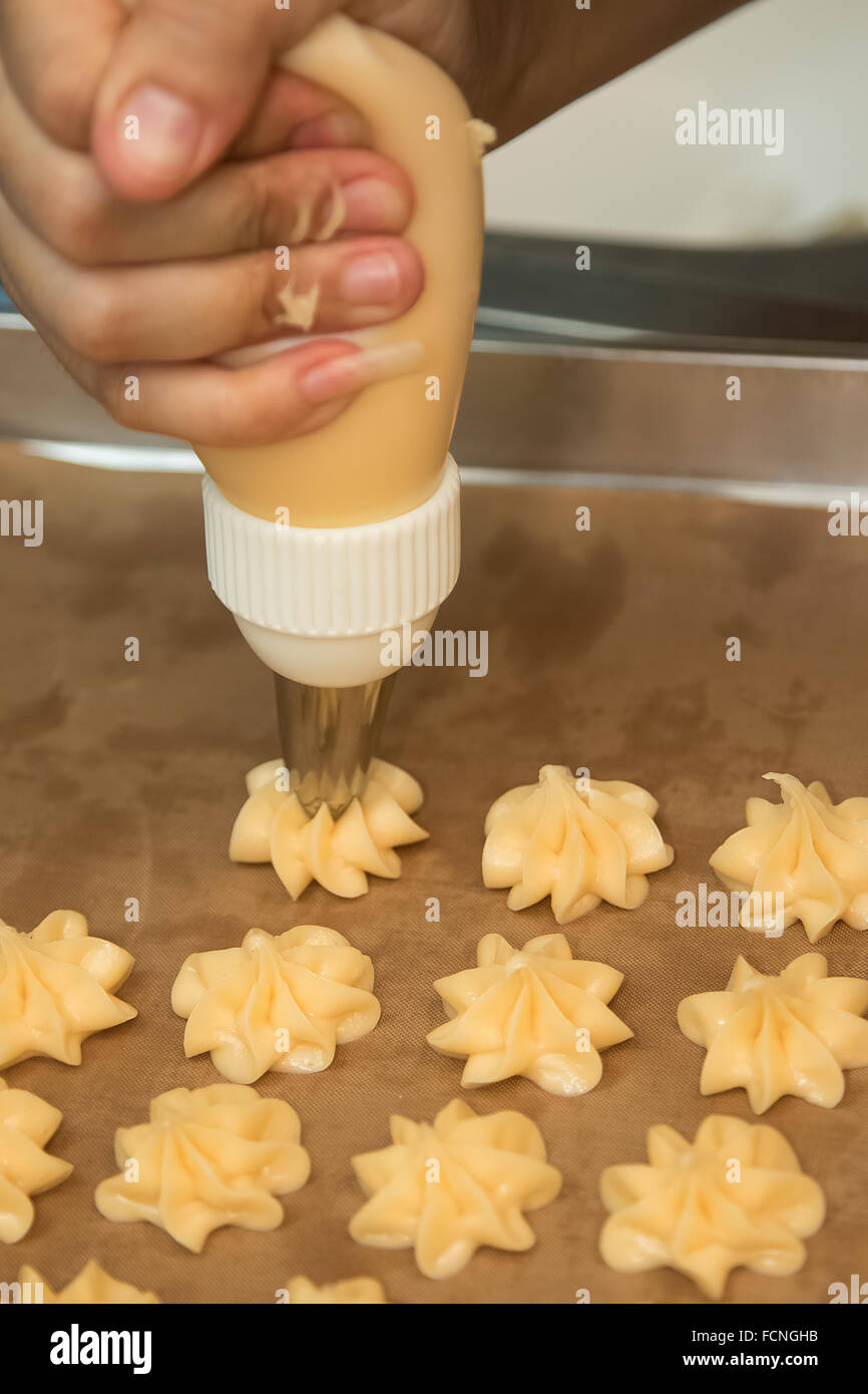 Making Eclair or choux pastry on to baking tray. Stock Photo