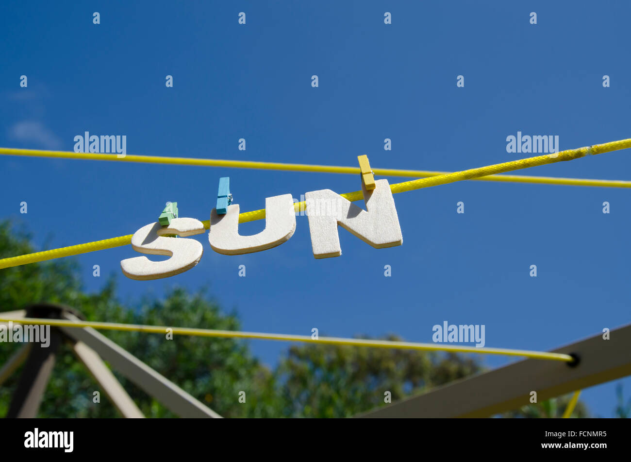 Letters forming the word SUN hanging from a clothesline with sunshine in the background, concept image for sunshine or sunny weather Stock Photo