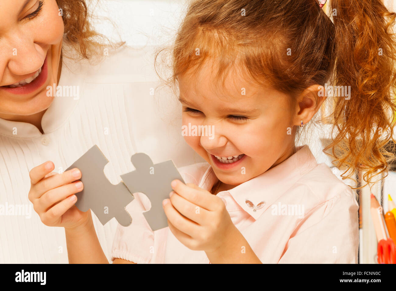 Little schoolgirl tries to assemble jigsaw puzzle Stock Photo