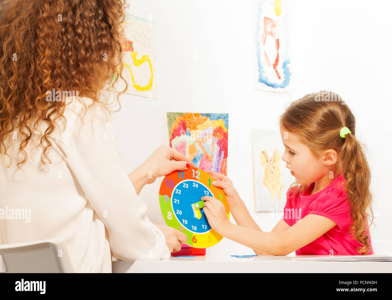 Girl moving pointers at the dial of clock model Stock Photo