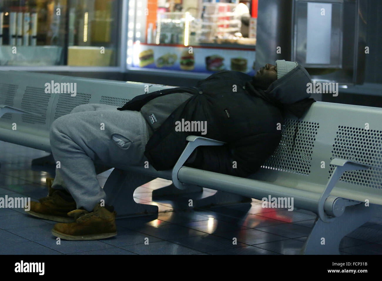 New York, New York, USA. 23rd Jan, 2016. A man sleeps in the Staten Island Ferry St. George terminal during Winter Storm Jonas. A travel ban had been in place for hours, but the ferry still operated. Snowfall projections for Staten Island were approximately 12-18in, with winds gusting up to 50 miles an hour. Late afternoon, buses ceased to run and a travel ban was enforced by the NYPD. This lack of transportation stranded many residents of Staten Island who had taken the ferry home. People were forced to try and walk to their destination in the blizzard. New York Governor Cuomo declared a Sta Stock Photo