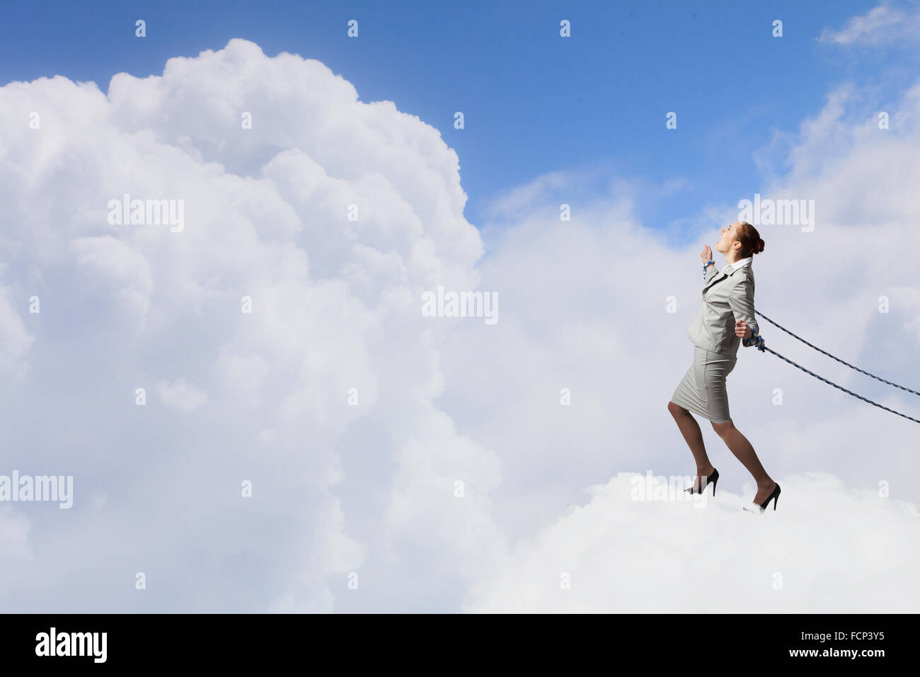Young businesswoman with ropes on hands trying to fly Stock Photo - Alamy