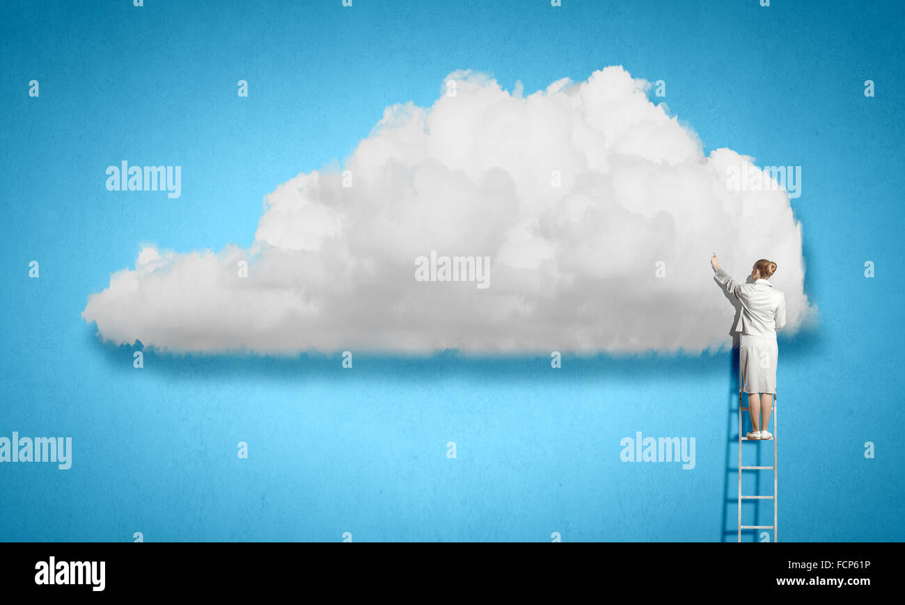 Back view of businesswoman standing on ladder and reaching to cloud ...