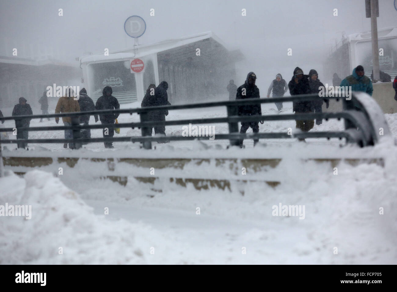 Staten Island, NY, USA. 23rd Jan, 2016. People walk away from the Staten Island Ferry St. George terminal during Winter Storm Jonas. A travel ban had been in place for hours, but the ferry still operated. Snowfall projections for Staten Island were approximately 12-18in, with winds gusting up to 50 miles an hour. Late afternoon, buses ceased to run and a travel ban was enforced by the NYPD. This lack of transportation stranded many residents of Staten Island who had taken the ferry home. People were forced to try and walk to their destination in the blizzard. New York Governor Andrew Cuomo de Stock Photo