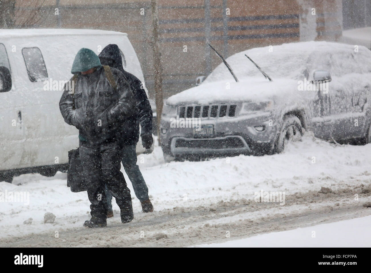 Staten Island, NY, USA. 23rd Jan, 2016. People walk away from the Staten Island Ferry St. George terminal during Winter Storm Jonas. A travel ban had been in place for hours, but the ferry still operated. Snowfall projections for Staten Island were approximately 12-18in, with winds gusting up to 50 miles an hour. Late afternoon, buses ceased to run and a travel ban was enforced by the NYPD. This lack of transportation stranded many residents of Staten Island who had taken the ferry home. People were forced to try and walk to their destination in the blizzard. New York Governor Andrew Cuomo de Stock Photo