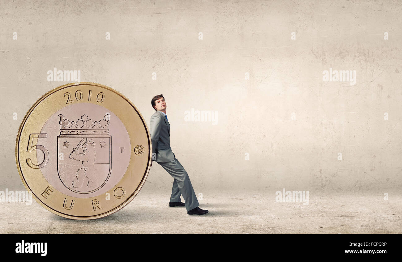 Young businessman rolling huge five euro coin Stock Photo