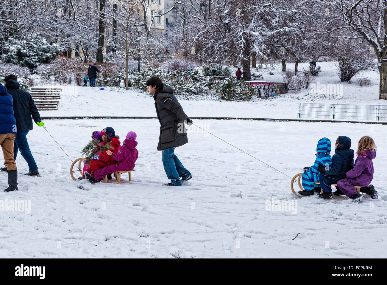 Berlin. Children pulled on sleds by parents after sledding in snowy Public park in winter, Volkspark am Weinbergsweg, Berlin Stock Photo