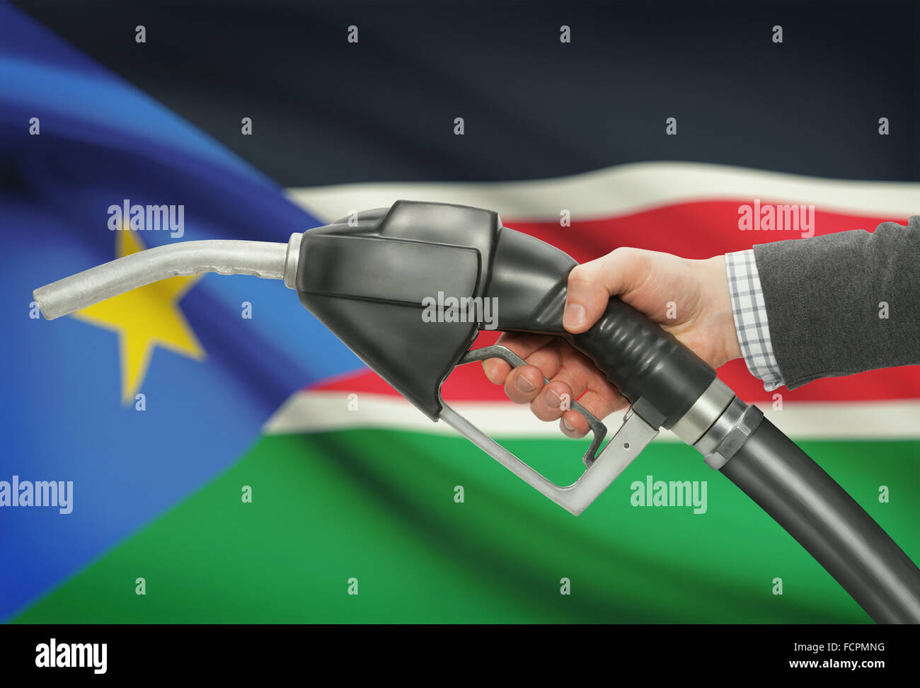 Fuel pump nozzle in hand with flag on background - South Sudan Stock Photo