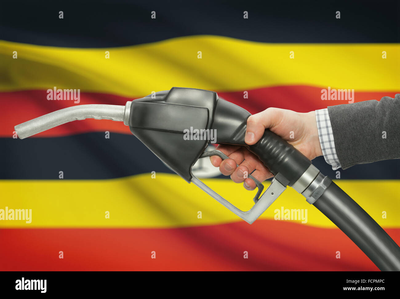 Fuel pump nozzle in hand with flag on background Uganda Stock Photo Alamy