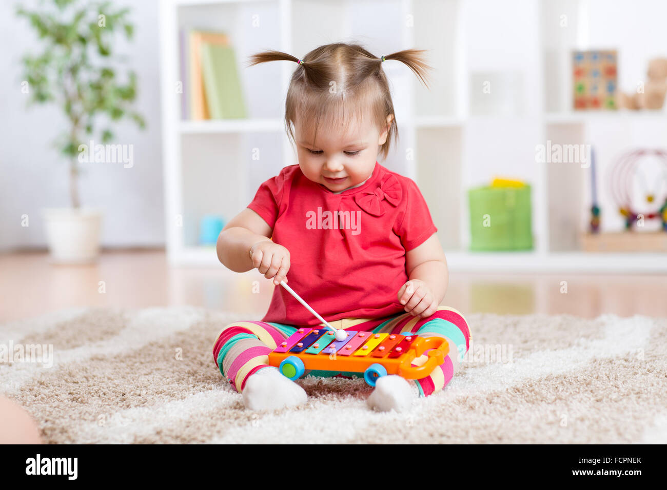 Child little girl plays a musical instrument xylophone Stock Photo